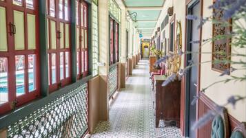 A corridor with patterned flooring, red-framed windows, and a green ceiling.