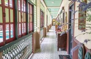 A corridor with patterned flooring, red-framed windows, and a green ceiling. - Ban Mai Vintage (Pak Chong)