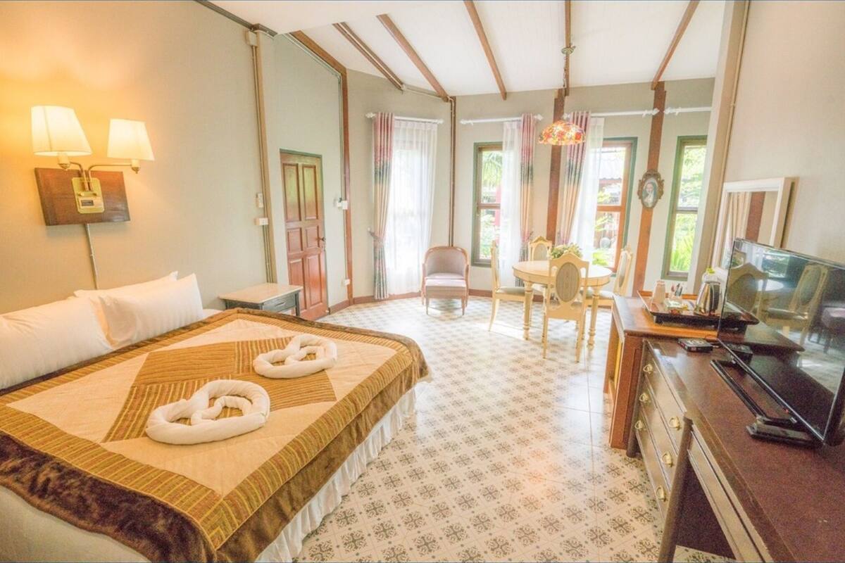 A hotel room with a bed, a desk, a chair, a television, and a lamp.