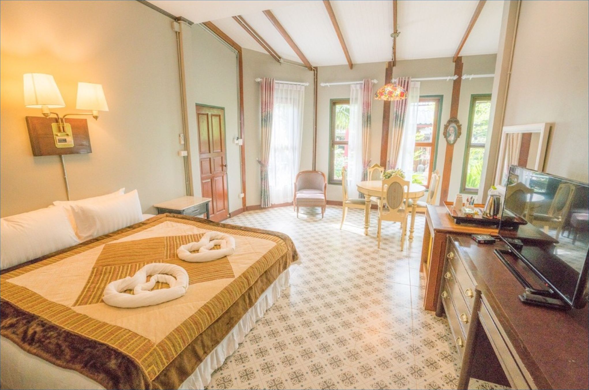 Una habitación de hotel con cama, escritorio, silla, televisor y lámpara.