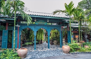 A traditional Thai covered walkway with a sign for a restaurant, stone flooring, and potted plants. - Ban Mai Vintage (Pak Chong)