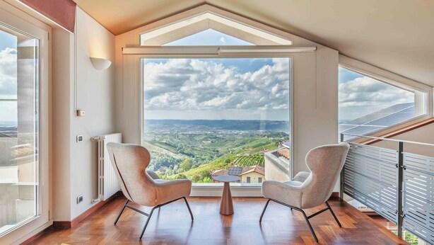 A room with a large skylight, two chairs, a small table, and a view of a landscape. - The Vista Retreat N.1 (Treiso)