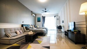 A modern living room with a sofa, a coffee table, a TV, and a ceiling fan. - Twin Galaxy Residence By The one - Johor Bahru (Johor Bahru)