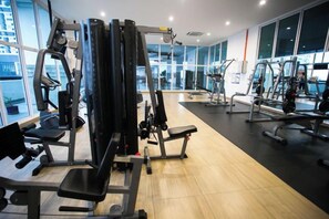 A gym with various exercise machines, large windows, and a wooden floor. - Twin Galaxy Residence By The one - Johor Bahru (Johor Bahru)