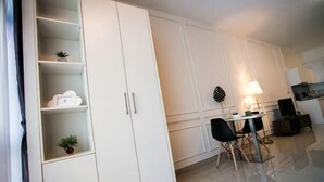 A modern kitchen with white cabinets, a dining area with a table and chairs, and a small plant on the countertop. - Twin Galaxy Residence By The one - Johor Bahru (Johor Bahru)