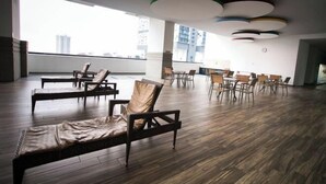 A spacious room with a high ceiling, a large window offering a city view, and a mix of seating areas including lounge chairs and tables. - Twin Galaxy Residence By The one - Johor Bahru (Johor Bahru)