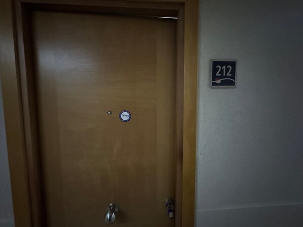 A wooden door with a CENSO sticker and a number 212 sign on the wall. - EDIFICIO BARCELONA (Temuco)