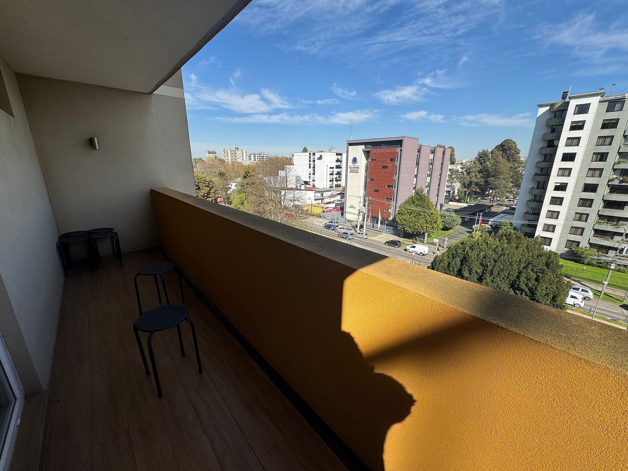 Un balcón con vista a un paisaje urbano, que incluye edificios y una calle.