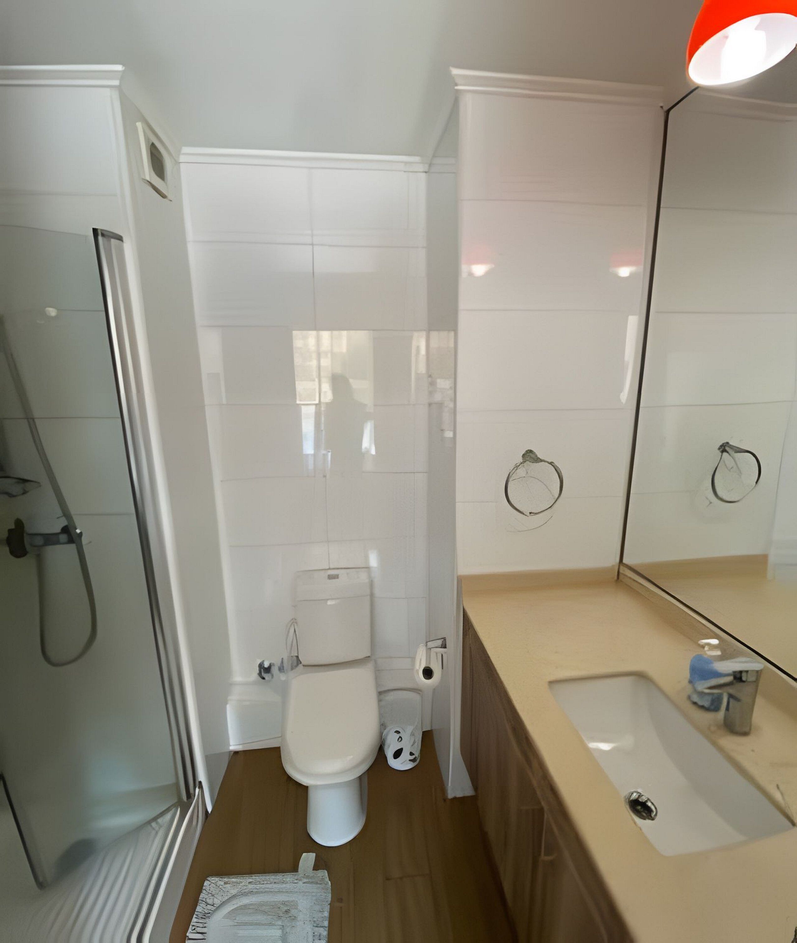 A modern bathroom with a toilet, shower, and sink.