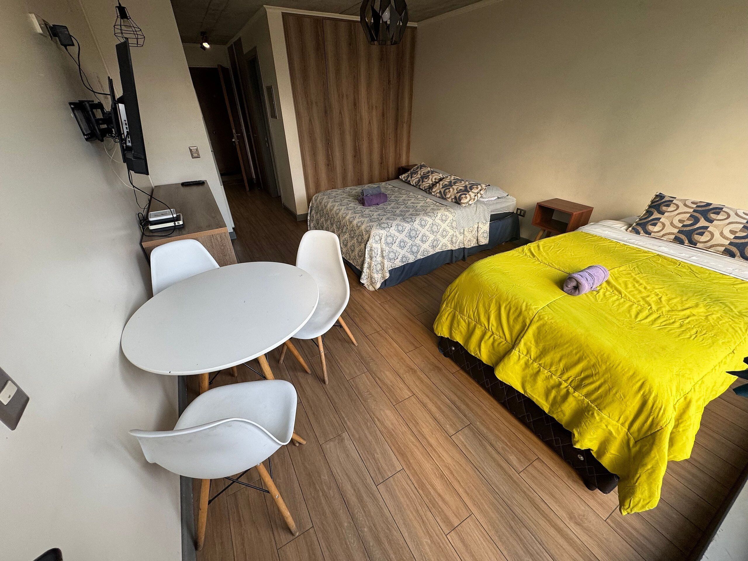 Un dormitorio con una cama, una mesa y dos sillas.