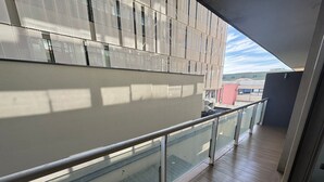 A modern building with a glass balcony and a metal railing. - EDIFICIO BARCELONA  (Temuco)