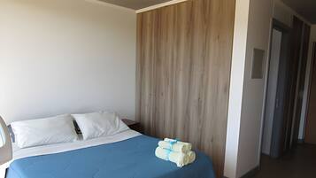 A bedroom with a bed, a wooden panel wall, and a hallway.