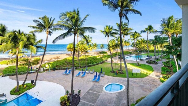 A resort with a pool, palm trees, and a view of the beach.