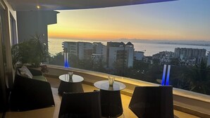 Un balcone con mobili in vimini e vista sulla città al tramonto.