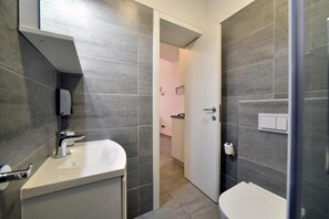 Une salle de bain moderne avec des carreaux gris, un lavabo blanc et des toilettes.