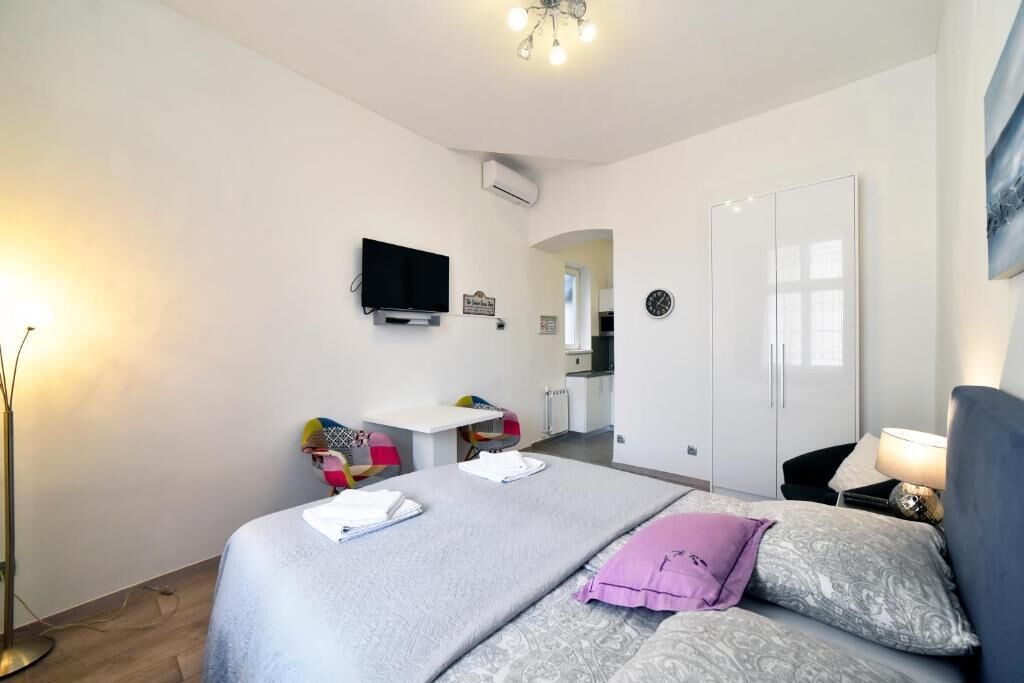 A modern bedroom with a bed, bedside table, and a TV mounted on the wall.