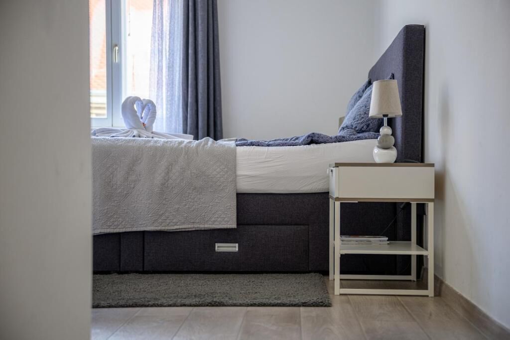 Un dormitorio moderno con cama, mesita de noche y vistas al exterior.