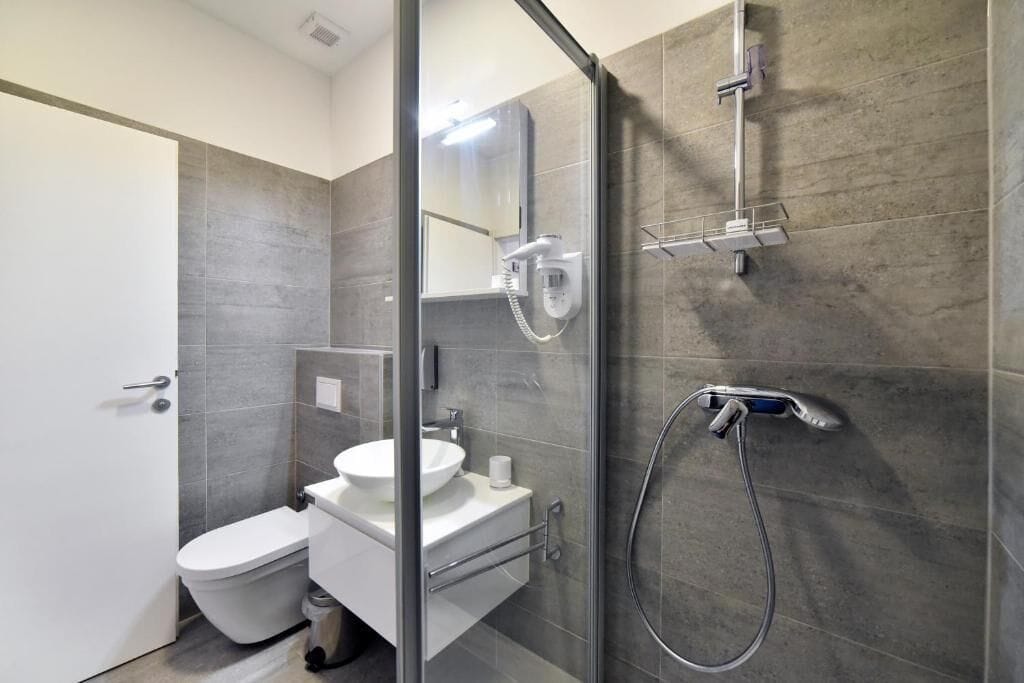 Un bagno moderno con box doccia in vetro, un water e un lavabo.