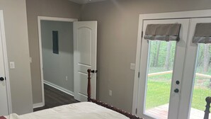 Ein Schlafzimmer mit Bett, Deckenventilator, Tür und Blick auf eine Terrasse.