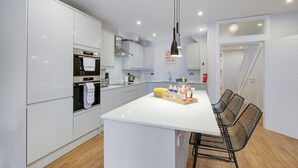 A modern kitchen with white cabinetry, a central island with seating, and a hanging pendant light.