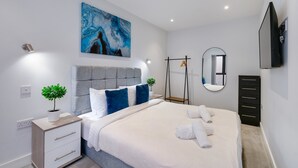 A modern bedroom with a bed, bedside table, and a large abstract painting.