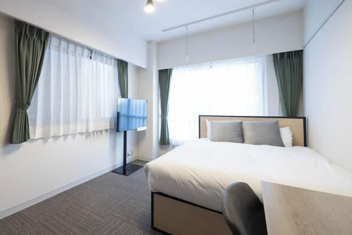 Une chambre d’hôtel avec un lit, un bureau et des rideaux aux fenêtres.