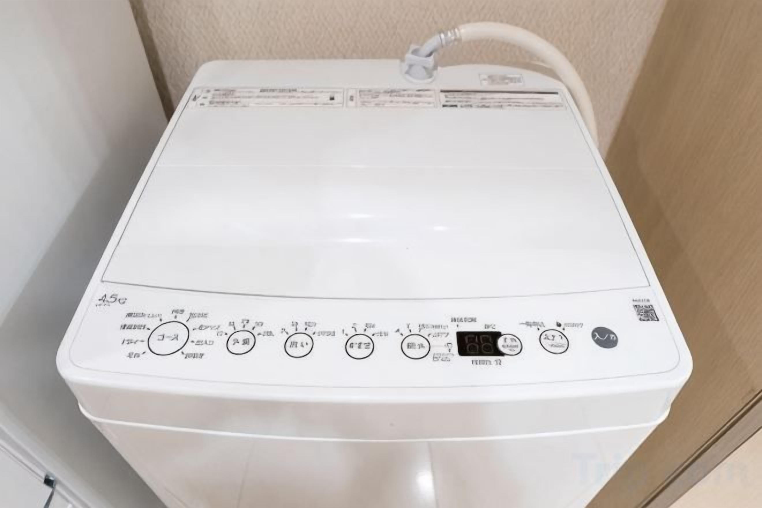 A white washing machine with control panel, power cord, and QR code.