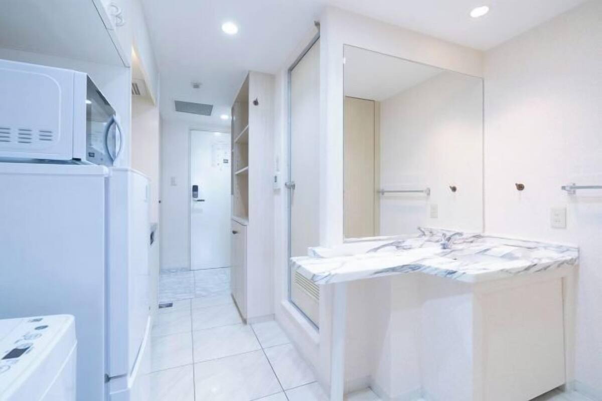 Une salle de bain moderne avec un grand miroir, un lavabo blanc et un lave-linge encastré.