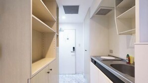 A narrow kitchen with a white door, a stainless steel sink, and a countertop. - Fujiterrace Yoga (Tokyo)