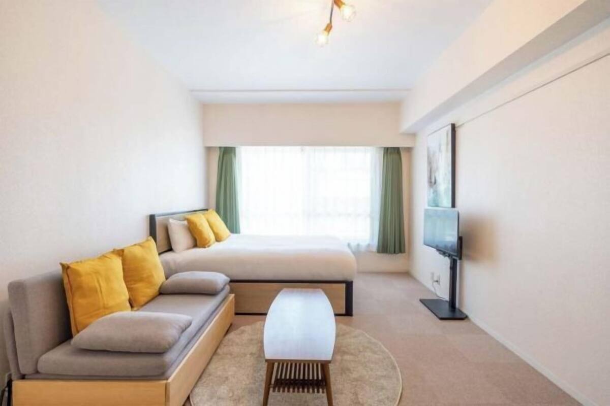 Une chambre d’hôtel moderne équipée d’un lit, d’un canapé, d’une télévision et d’une petite table.