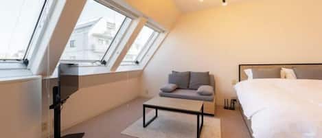 A modern bedroom with a bed, a sofa, a desk, and a ceiling light.