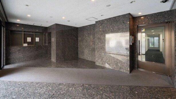 A modern lobby with a polished granite floor, a glass door entrance, and a ceiling with recessed lighting. - Fujiterrace Yoga (Tokyo)