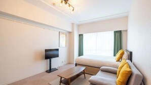 A hotel room with a bed, a sofa, a TV, and a desk. - Fujiterrace Yoga (Tokyo)