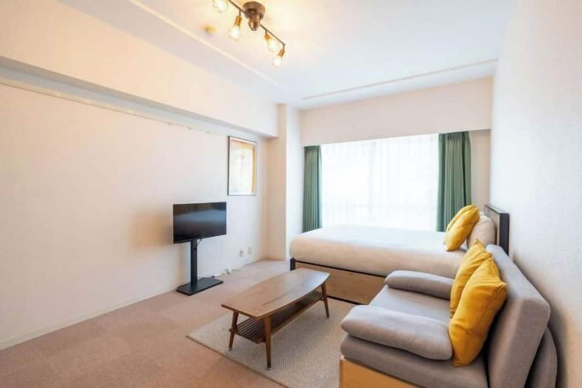 Une chambre d’hôtel avec un lit, un canapé, une télévision et un bureau.