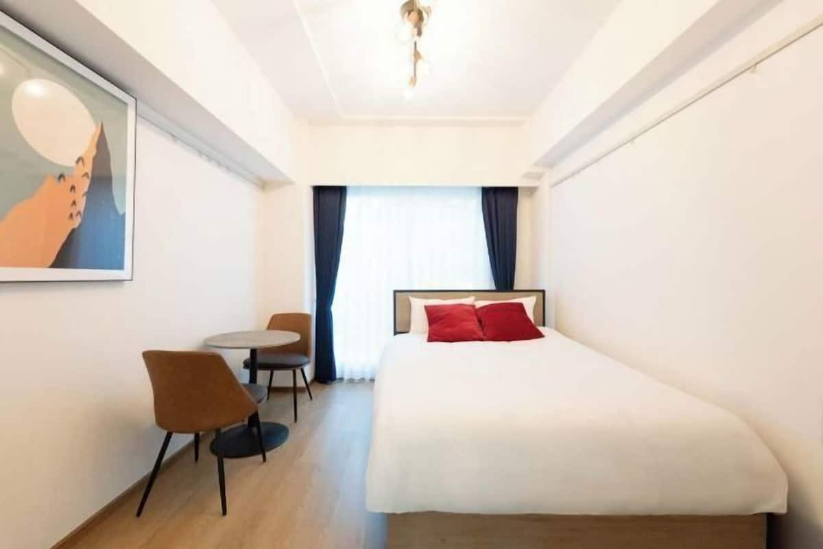Une chambre d’hôtel avec un lit, une chaise, une table et un tableau au mur.