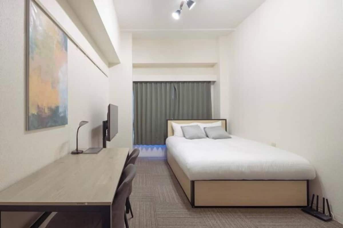 Une chambre d’hôtel avec un lit, un bureau, une chaise, une télévision et un tableau au mur.