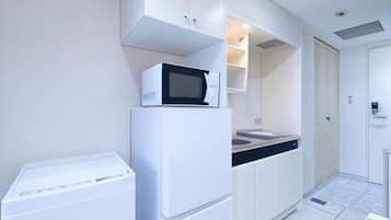 A compact kitchen with a microwave on a white appliance, a small sink, and a door with a lock.