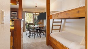 A cozy room with a bunk bed, a dining table with chairs, and a chandelier. - Outpost: Larkspur 1212 (Wilson)