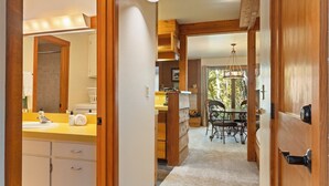 A modern kitchen with wooden cabinets, a yellow countertop, and a dining area with a chandelier. - Outpost: Larkspur 1212 (Wilson)