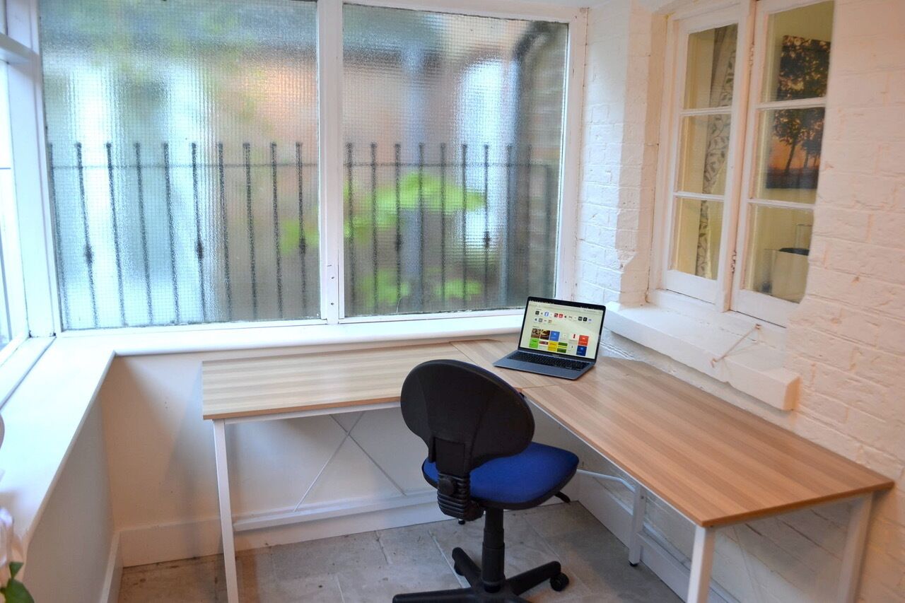 Un pequeño espacio de oficina con un escritorio, una silla y un ordenador portátil.