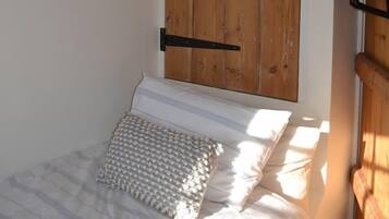 A bedroom with a bed, a wooden door, and a small wooden shelf.