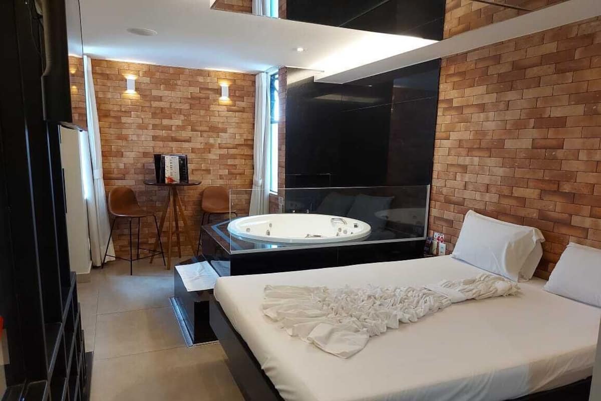 Une chambre d’hôtel moderne dotée d’un grand lit, d’un coin salon avec une table et des chaises, et d’une grande fenêtre.
