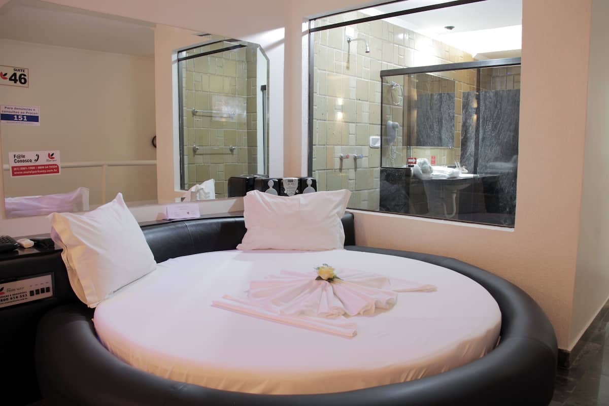 Une chambre d’hôtel avec un lit, une table de chevet, un miroir et une vue sur la salle de bain.