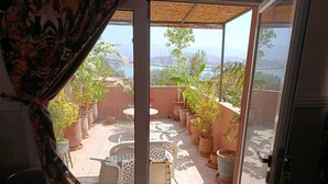 A balcony with potted plants, a chair, and a table. - TIKI HOUSE  (Lalla Takarkoust)