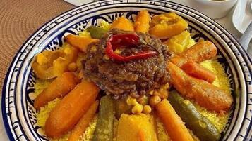 Un plato de cuscús con verduras y un guiso de carne, servido en un plato estampado.