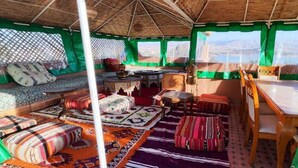 A cozy interior with a sofa set, a dining table, and a view of the mountains. - TIKI HOUSE  (Lalla Takarkoust)