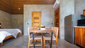 A modern kitchen with a wooden dining table, chairs, and a refrigerator. - Bali-Style Jungle Bungalow, salt water pool, near beaches. (Ojochal)