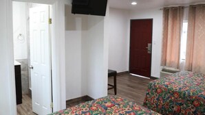 A room with two beds, a TV, a door, and a window with curtains.