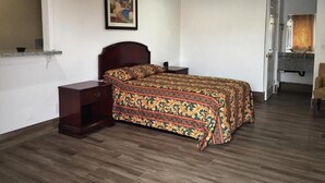 A bedroom with a bed, nightstands, a painting on the wall, and a bathroom visible through an open door.
