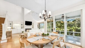 Una cocina moderna con armarios blancos, horno empotrado y un amplio ventanal con vistas a un jardín.